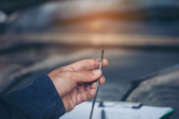 Car Mechanic man hand checking dipstick engine oil car mechanical on site service. Close up hand man check engine oil level Locate dipstick, wipe clean, check dipstick level before fill up engine oil