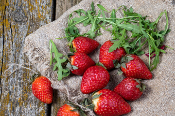 Strawberries with greens against the background of old boards