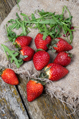 Strawberries with greens against the background of old boards