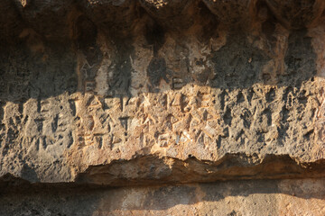 Ancient sandstone tomb carves in cave. Handwritten ancient inscription on rock formations.