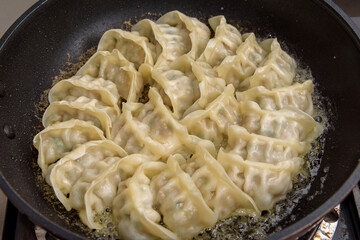 Baked dumplings being cooked in a frying pan