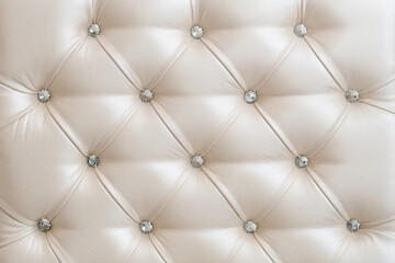 Carriage furniture upholstery in light beige leather with fittings from white crystals, background
