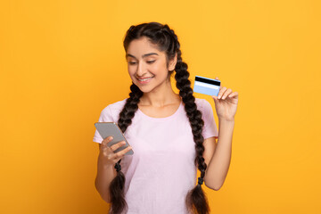 Young indian woman holding credit card and smartphone