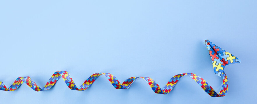Autism awareness. paper plane in origami style with autism awareness ribbon on blue background.
