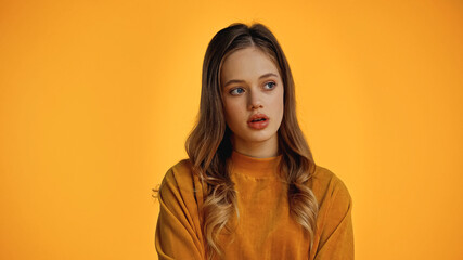 thoughtful teenage girl in sweatshirt looking away isolated on yellow