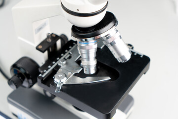 Close up of white microscope in science laboratory on white table. Microscope for chemistry, biology, test, samples, examining, medical, equipment and education.
