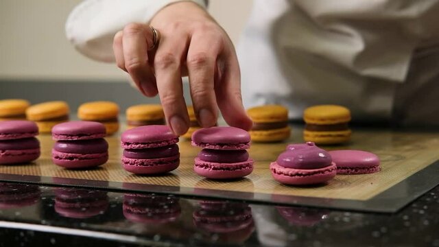 The pastry chef assembles macarons with strawberry cream, the most delicious dessert.