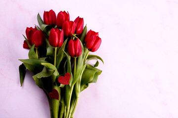 Red tulips bouquet and red hearts on a pink background. Valentine's Day, Woman's Day and Mother's Day concept. View from the top