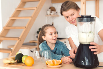 funny face kid make smoothie in blender with mother