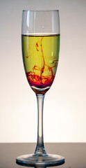 White wine in champagne glass with red bloody stream floating to the bottom