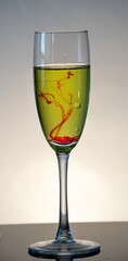 White wine in champagne glass with red bloody stream floating to the bottom