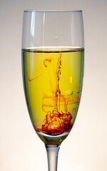 White wine in champagne glass with red bloody stream floating to the bottom