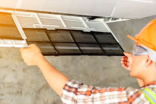 Technician installing an air conditioning unit on a wall, Thailand