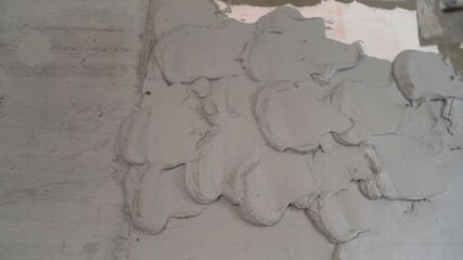 A builder applies plaster with a trowel to a concrete wall to anchor the metal building beacon. The...