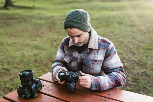 Photographer with a camera in his hands while sitting at an outdoor table with another camera