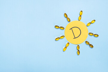 Vitamin D concept, nutritional supplement and health. Yellow capsules in form of the sun and letter...