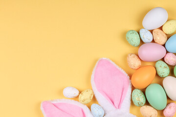 Easter yellow background with colorful eggs and bunny ears. 