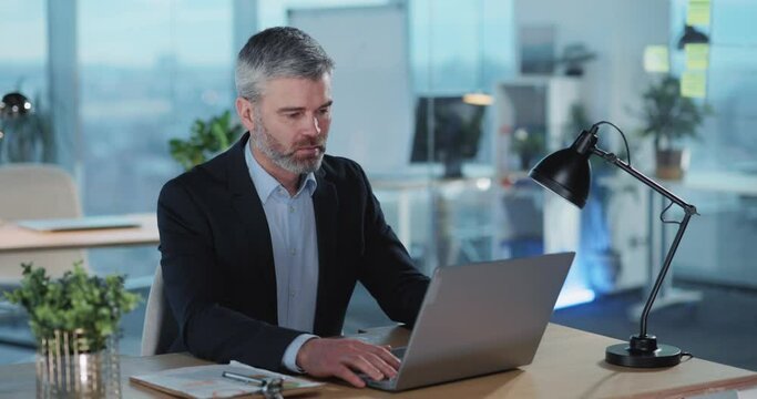Middle aged businessman adult employer working by laptop computer in office room. Business people. Employment, occupation.