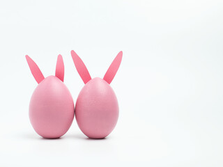 Naklejka na ściany i meble Two Easter pink eggs with bunny ears on a white background. Happy Easter concept. Copy space