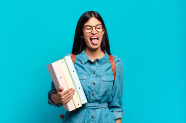 young hispanic student woman with cheerful, carefree, rebellious attitude, joking and sticking...