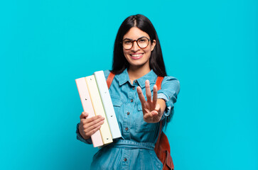 young hispanic student woman smiling and looking friendly, showing number three or third with hand...