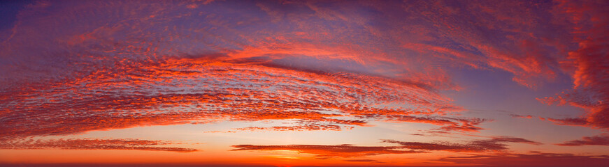 Fototapeta premium intense dramatic panoramic sunset with cirrus clouds illuminated by red sunbeams