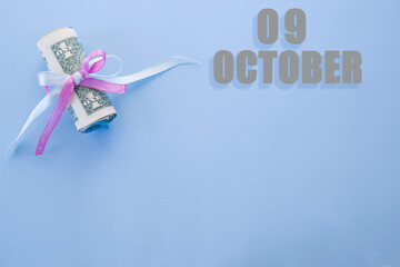 calendar date on blue background with rolled up dollar bills pinned by blue and pink ribbon with...