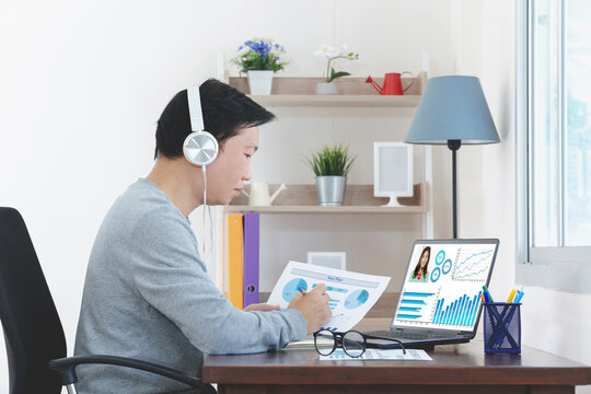 Online video conference. Successful young adult businessman or manager with headphones discuss with colleagues by video call about financial graphs and strategy and another working - Powered by Adobe