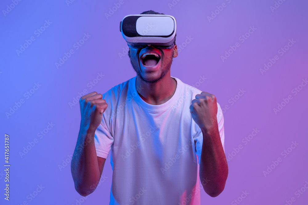 Wall mural overjoyed african american man in vr glasses celebrating win in video game