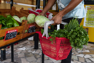 Homem segurando cesta de frutas e legumes no mercado.