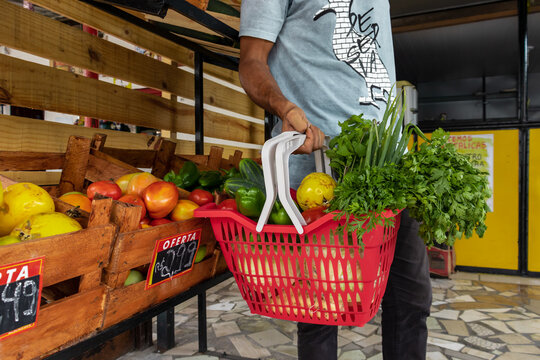 Homem segurando cesta de frutas e legumes no mercado.