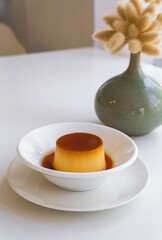 Pudding caramel custard in White ceramic bowl on  white table.