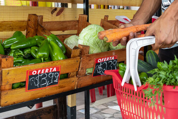 Homem segurando cesta de frutas e legumes no mercado.
