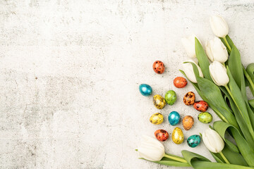 Top view of white tulips and colored easter eggs on concrete backgrund with copy space