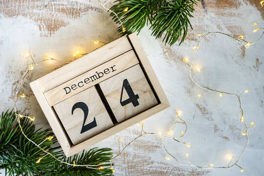 Wooden block calendar for Christmas Eve with fairy lights and fir branches