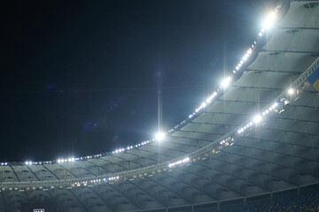 Stadium lit floodlighting into the darkness of the evening. Bokeh effect.