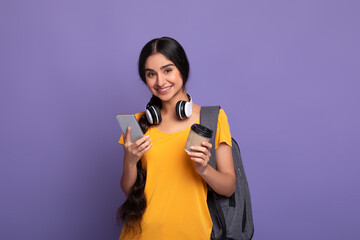 Indian female student holding mobile phone and coffee