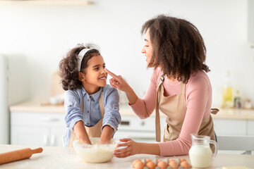 Black woman and his daughter cooking and playing with flour