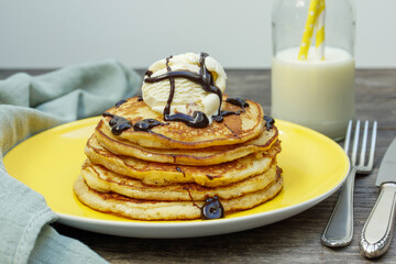pancakes with ice cream and chocolate sauce on a yellow plate