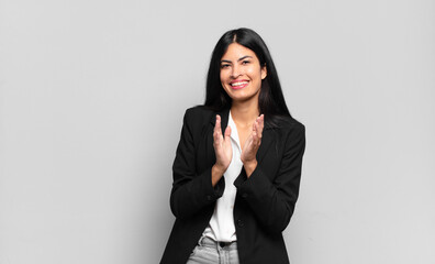 young hispanic businesswoman feeling happy and successful, smiling and clapping hands, saying...