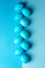 row of Easter eggs on a colored background with copy space.