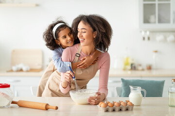 Obraz na płótnie Canvas Happy black woman and child daughter mixing dough