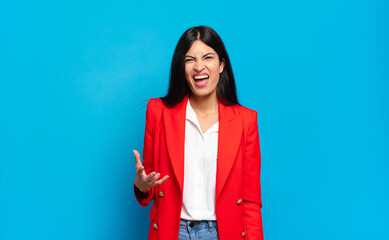 young hispanic businesswoman looking angry, annoyed and frustrated screaming wtf or what’s wrong...