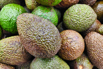 Close-up on a stack of avocados on a market stall.