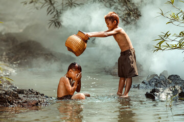 Two boys washing in a river, Thailand