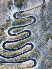 Winding road aerial view by drone. Brasov, Romania. There are huge snow mountains and long winding road in this area. This is a great place to drive and stop during a road trip.