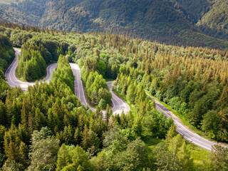 Winding road aerial view by drone. Brasov, Romania. There are huge snow mountains and long winding road in this area. This is a great place to drive and stop during a road trip.