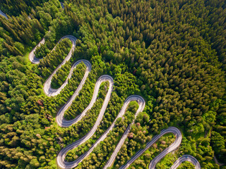 Winding road aerial view by drone. Brasov, Romania. There are huge snow mountains and long winding road in this area. This is a great place to drive and stop during a road trip.