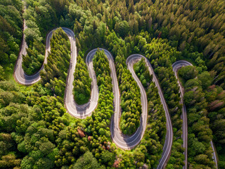 Winding road aerial view by drone. Brasov, Romania. There are huge snow mountains and long winding...