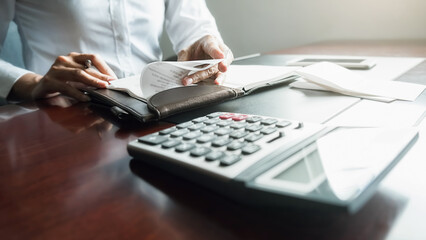 Woman with bills and calculator. Woman using calculator to calculate bills at the table in office....